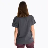 Remera de manga corta color gris oscuro con cuello redondo. Presenta un estampado gráfico central en tonos violeta, rosa y blanco con la inscripción 'MERRELL OUTDOOR' y 'LIFE IS NOW'.