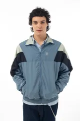 Campera deportiva azul con recortes en negro y verde agua, cierre frontal con cremallera y cuello tipo mao.