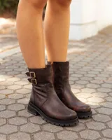 Botas de caña media color marrón con acabado desgastado, confeccionadas en cuero. Presentan una suela chunky dentada, cierre lateral y dos correas decorativas con hebillas metálicas en el lateral exterior.