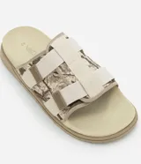 Ojota tipo slide con estampa camuflada en tonos beige y marrón. Presenta dos tiras ajustables con cierre de velcro y suela de goma antideslizante.