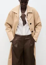 Pantalón wide leg de efecto piel color marrón, con tiro medio, bolsillos laterales, pinzas delanteras y cierre frontal con botón, gancho y cremallera ocultos. Cuenta con forro interior.