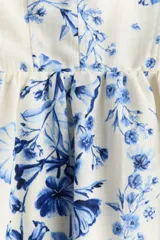 Vestido midi de tejido liviano color blanco con estampado floral en tonos azules, escote cuadrado, breteles finos y falda con vuelo.