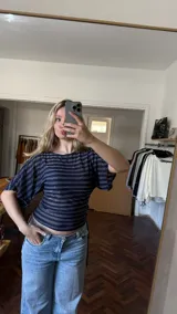 Remera de manga corta ajustada en la cintura, confeccionada en jersey rayado con brillo en tonos azul y plateado, con diseño de rayas horizontales y mangas amplias.