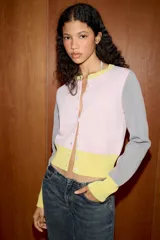 Chaqueta de punto con diseño color block, cuello redondo y manga larga. Presenta cuerpo en color rosado con franja inferior amarilla, mangas grises con puños amarillos y cierre frontal con botones.