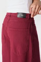 Jean de corte wide leg en color bordó, confeccionado en denim de algodón. Presenta tiro medio, bolsillos traseros amplios y una silueta holgada y fluida.