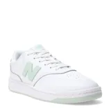 Championes New Balance de estilo urbano, confeccionados en cuero y materiales sintéticos. Presentan un diseño de silueta limpia en color blanco con detalles en verde menta en el logo lateral, la lengüeta y la suela. Cuentan con cierre de cordones y plantilla de EVA para mayor amortiguación.
