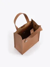 Cartera tipo tote pequeña de cuero color tostado, con doble asa superior y herrajes metálicos plateados en forma de llama en la base de las manijas. Presenta el logo de la marca estampado en la parte inferior frontal.