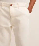Pantalón recto de sarga color blanco roto, con cintura con trabillas, cierre frontal tradicional y bolsillos laterales y traseros.
