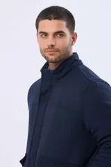 Saco de paño azul marino con capucha desmontable, cierre frontal oculto, bolsillos laterales con tapa y detalles en los puños.