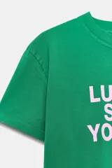 Remera de algodón color rosado con efecto lavado, de corte regular y cuello redondo, con texto rojo estampado en el frente que dice 'CENTER OF ATTENTION'.
