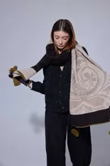 Chal de lana con diseño de patrón paisley y detalles de tejido en punto. Presenta terminaciones con pompones en los extremos.