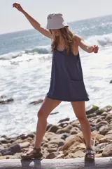 Vestido corto de tirantes finos, color negro con efecto acid wash, escote redondo y espalda cruzada. Cuenta con bolsillos de parche grandes en la parte delantera y un forro interior con costuras para shorts.