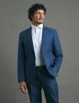 Ambo slim fit de color azul, compuesto por saco de dos botones y pantalón de vestir a juego. El tejido cuenta con elastano para mayor comodidad y flexibilidad.