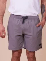 Short de baño gris liso con cintura elástica y cordón ajustable bicolor en contraste. Cuenta con bolsillos laterales y una pequeña etiqueta decorativa en el dobladillo.