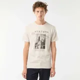 Remera beige de manga corta con estampado de una ciudad y texto en blanco y negro.