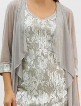 Conjunto de dos piezas compuesto por un vestido midi de silueta recta con tejido plisado metalizado y escote redondo con pedrería, acompañado por una chaqueta de gasa abierta con caída en cascada y mangas tres cuartos con puños metalizados.
