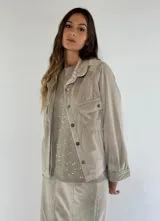 Chaqueta color beige con cuello camisero, cierre frontal con botones, bolsillos de parche con solapa y manga larga.