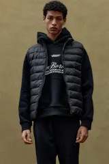 Chaleco negro acolchado con cuello alto y cierre frontal. Diseño sin mangas con bolsillos laterales con cierre y bolsillos interiores abiertos.