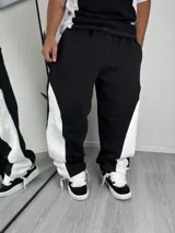 Pantalón tipo jogger de corte baggy, color negro con paneles laterales en color blanco. Presenta cintura elástica y diseño holgado.