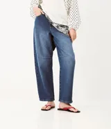 Pantalón baggy de jean azul con tiro medio, corte holgado, recortes en las rodillas y llavero decorativo con perlas y dije de corazón.
