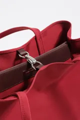 Bolso shopper de gran capacidad confeccionado en nylon color marrón, con estructura blanda, doble asa de mano y logo metálico de la marca en la parte frontal. Incluye cierre con mosquetón y bolsillo interior.