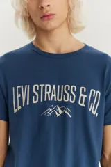 Remera de manga corta color azul, con cuello redondo y estampado frontal con el logo de la marca y un diseño de montañas.