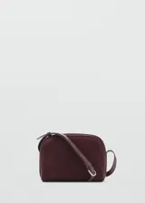Bolso bandolera de tamaño pequeño confeccionado en piel de serraje color bordó, con cierre de cremallera y asa larga ajustable.