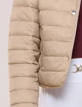 Campera puffer corta de diseño reversible y liviano, marca Michael Kors. Cuenta con acabado resistente al agua, diseño acolchado con matelaseado horizontal, cuello redondo a la base sin solapa ni capucha, cierre frontal completo con botones de presión metálicos, bolsillos laterales funcionales y ribetes a tono. Largo a la cintura y empacable en su propia bolsa de guardado.