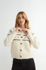 Cardigan de punto color beige con textura suave, cuello redondo y cierre frontal con botones tipo cuerno. Presenta un diseño de rayas horizontales oscuras y pequeños bordados de flores en la parte superior del pecho.