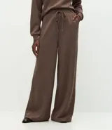 Pantalón de corte recto con cintura estructurada y lazo ajustable. Presenta un diseño básico y versátil con aberturas laterales en el ruedo.