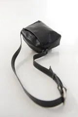 Bandolera semirrígida Sagali de cuero vacuno color bordó, con textura de cocodrilo en el bolsillo frontal y cuerpo liso. Cuenta con cierre superior y correa regulable.