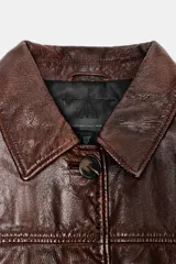 Chaqueta de cuero vacuno con acabado efecto lavado, cuello solapa, cierre frontal con botones y bolsillos delanteros con solapa. Presenta un corte recto y forro interior.