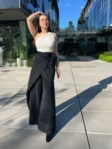 Pantalón negro de vestir con corte palazzo, cintura alta con lazo y abertura lateral.