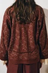 Kimono color ladrillo con bordado floral, confeccionado en lino. Tiene mangas largas, cinturón ajustable con lazadas y detalle de abalorios.