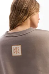 Buzo de algodón color crema, con cuello redondo, mangas largas y calce relajado. Presenta el logo de la marca bordado en el centro del pecho.