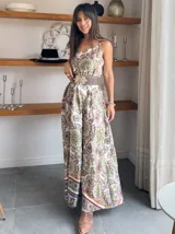 Vestido largo de satén con estampado de mandalas en tonos blanco, verde, marrón y naranja. Tiene breteles finos y corte imperio con cinturón marrón con hebilla dorada.