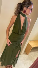 Vestido largo de microtul color verde militar, con escote profundo en V, cuello halter y detalle de choker incorporado. Falda cruzada con frunces laterales, tajo pronunciado con volados y transparencias.