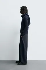 Pantalón de corte balloon fit, color negro, con bolsillos laterales de vivo y bolsillos traseros con solapa. Presenta cierre frontal con cremallera y botón.