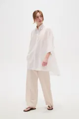 Camisa de lino blanca de corte holgado, con cuello camisero y mangas tres cuartos, diseñada con estilo casual.