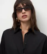Camisa básica de mujer confeccionada en tricolina de algodón, con cuello solapa, cierre frontal de botones y mangas largas con puños abotonados.
