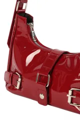 Bandolera de charol color rojo, con diseño estilo baguette. Presenta cierre superior, correas ajustables con hebillas metálicas y detalles decorativos de hebillas en la parte frontal.