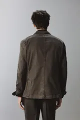 Blazer de corte relajado confeccionada en mezcla de algodón con acabado efecto lavado. Presenta cuello con solapas de muesca, cierre frontal con dos botones, bolsillo de vivo en el pecho y bolsillos con solapa en la cadera. Diseño sin forro interior con aberturas en la espalda.