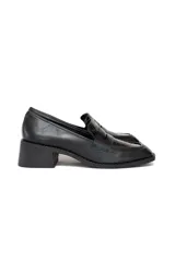Zapato tipo mocasín de cuero negro con acabado brillante y panel central texturizado con relieve tipo cocodrilo. Presenta punta cuadrada y tacón bajo cuadrado.