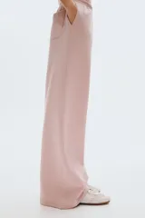 Pantalón de jogging de corte ancho y tiro alto, confeccionado en tejido de felpa con interior cepillado suave. Presenta cintura elástica fruncida con cordón de ajuste oculto, bolsillos laterales discretos y un bolsillo trasero abierto.