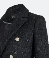 Blazer negro de tweed con hilos metalizados, corte entallado, escote en V profundo, bolsillos delanteros con solapa y doble botonadura con seis botones decorativos de strass.