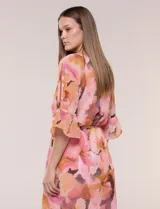 Vestido corto de gasa semitraslúcida con estampado floral en tonos rosados, naranjas y marrones. Posee escote en V, mangas tres cuartos acampanadas con abertura, y un fino lazo ajustable en la cintura. Incluye forro interior a tono.
