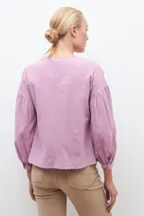 Blusa blanca de manga larga con escote en V y bordados en el frente.