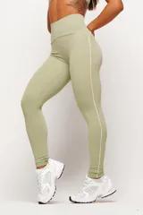 Conjunto deportivo de dos piezas en color verde pistacho, compuesto por un top de tirantes finos con escote recto y una calza larga de tiro alto con detalles de líneas en contraste.