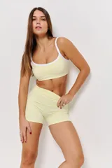 Conjunto deportivo de dos piezas color amarillo limón, compuesto por un top con breteles finos y bordes blancos, y un short ajustado de tiro medio.