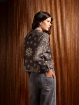 Buzo de punto de manga larga con cuello redondo, confeccionado en un tejido suave de textura peluda. Presenta un diseño estampado con motivos florales y ornamentales en color negro sobre una base de color rojo intenso.